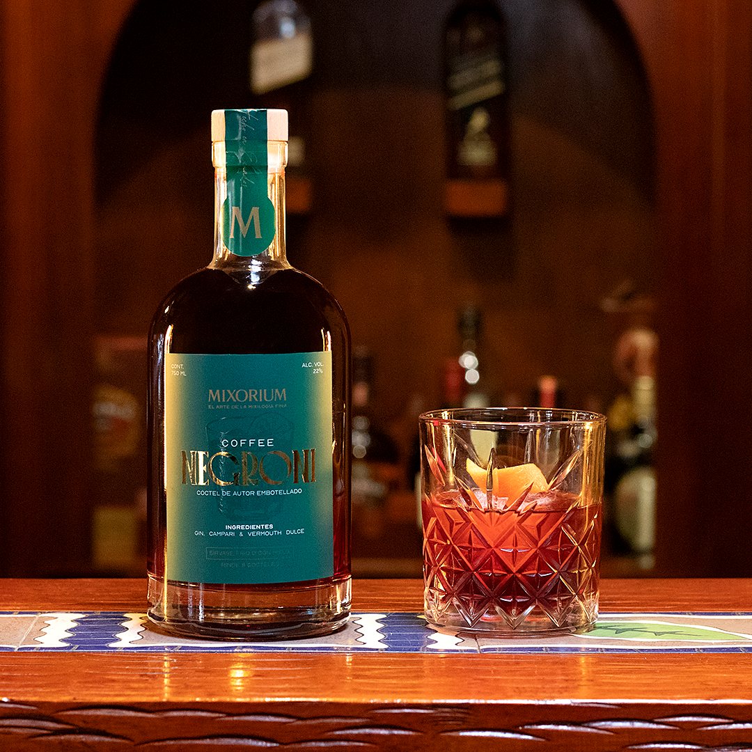 Botella de Coffee Negroni junto a un vaso con el cóctel servido
